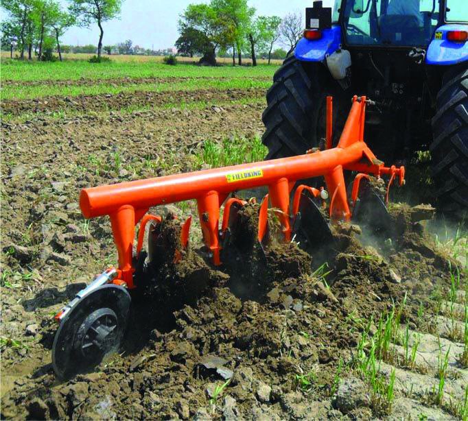 A green tractor is seen plowing a cassava field under a bright blue sky with scattered clouds, symbolizing agricultural mechanization and productivity